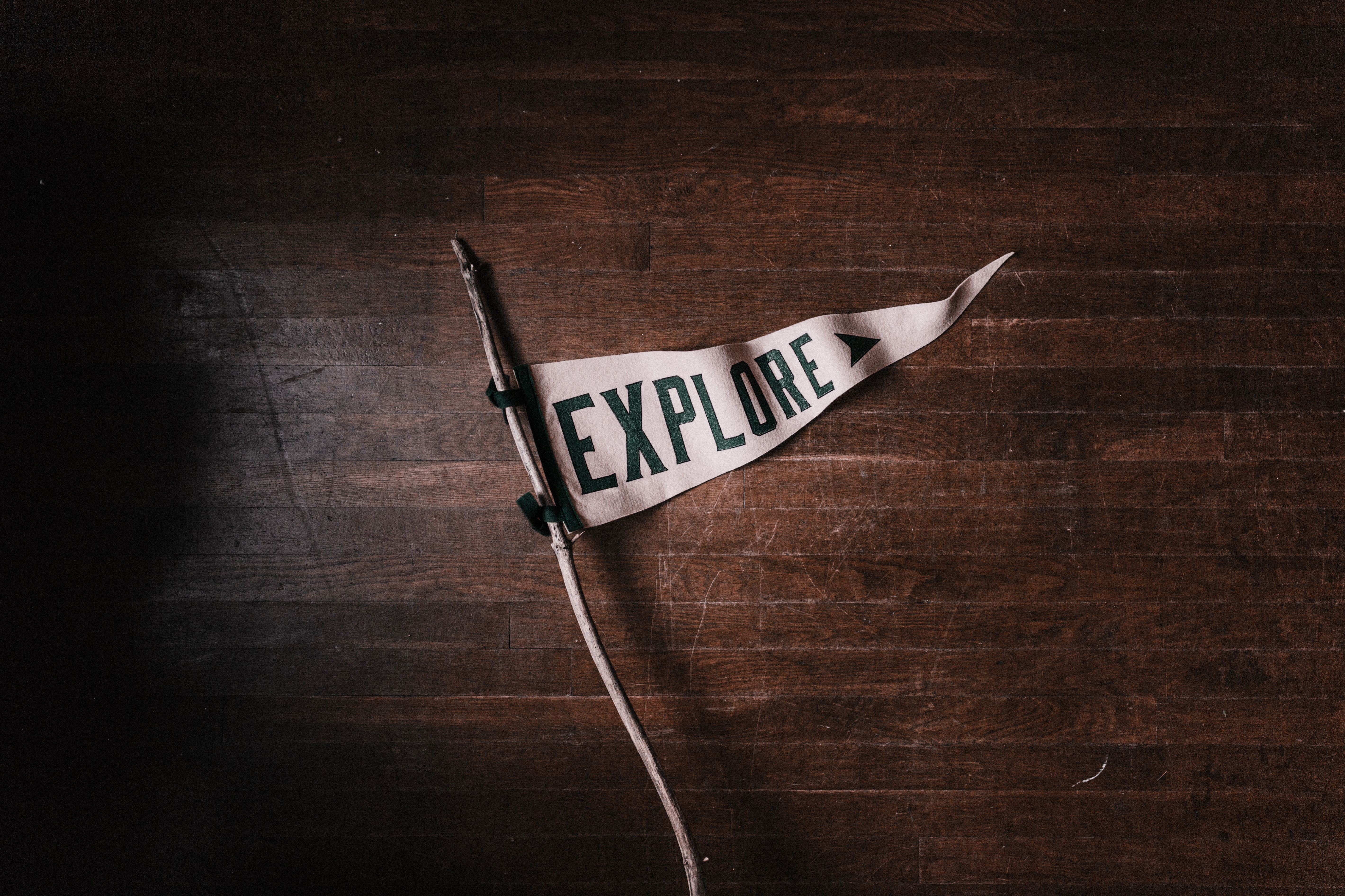 A white pennant that says explore on a dark wooden floor