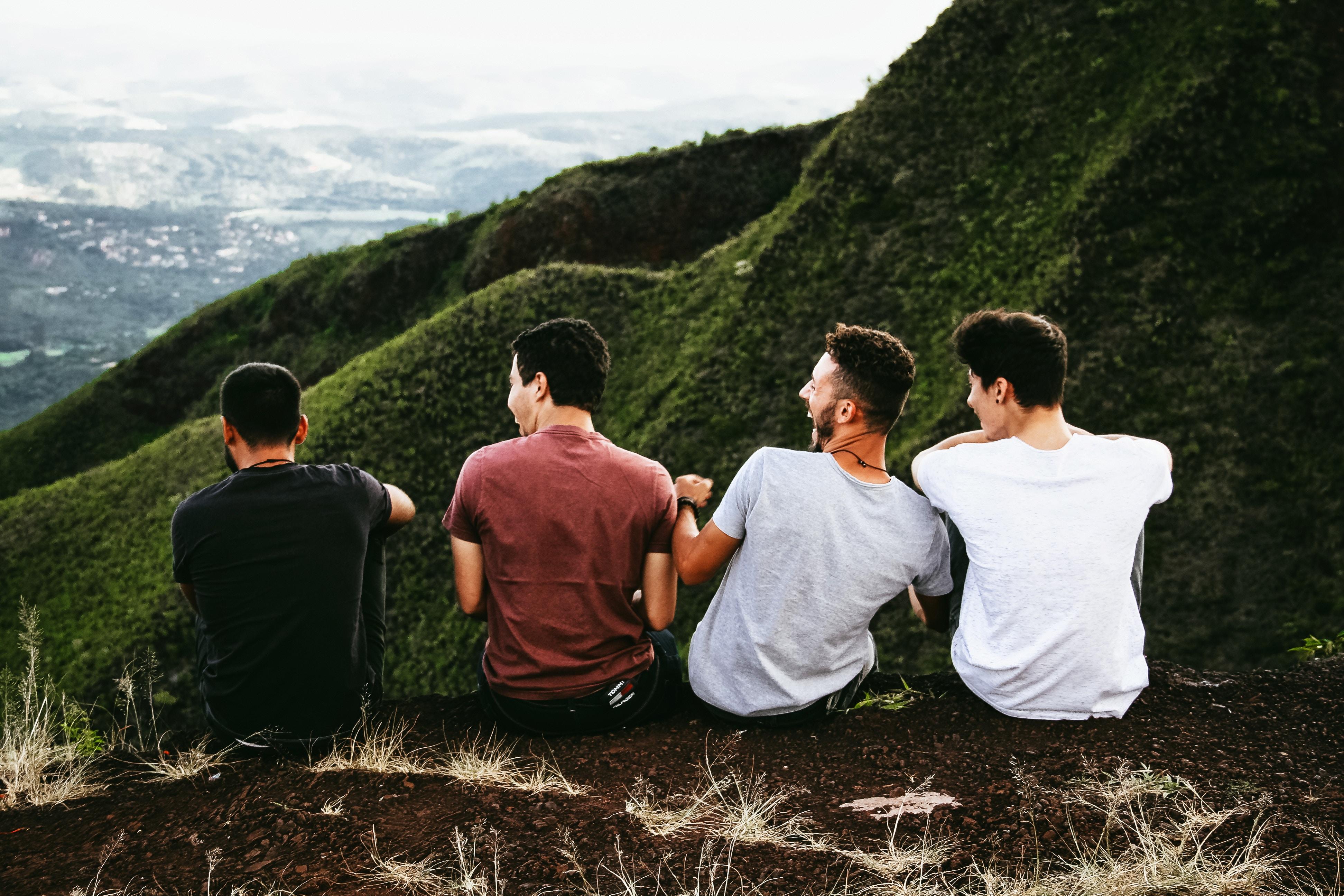 Czterech młodych mężczyzn siedzi na skraju zbocza, widać, że dobrze się bawią i są zrelaksowani.